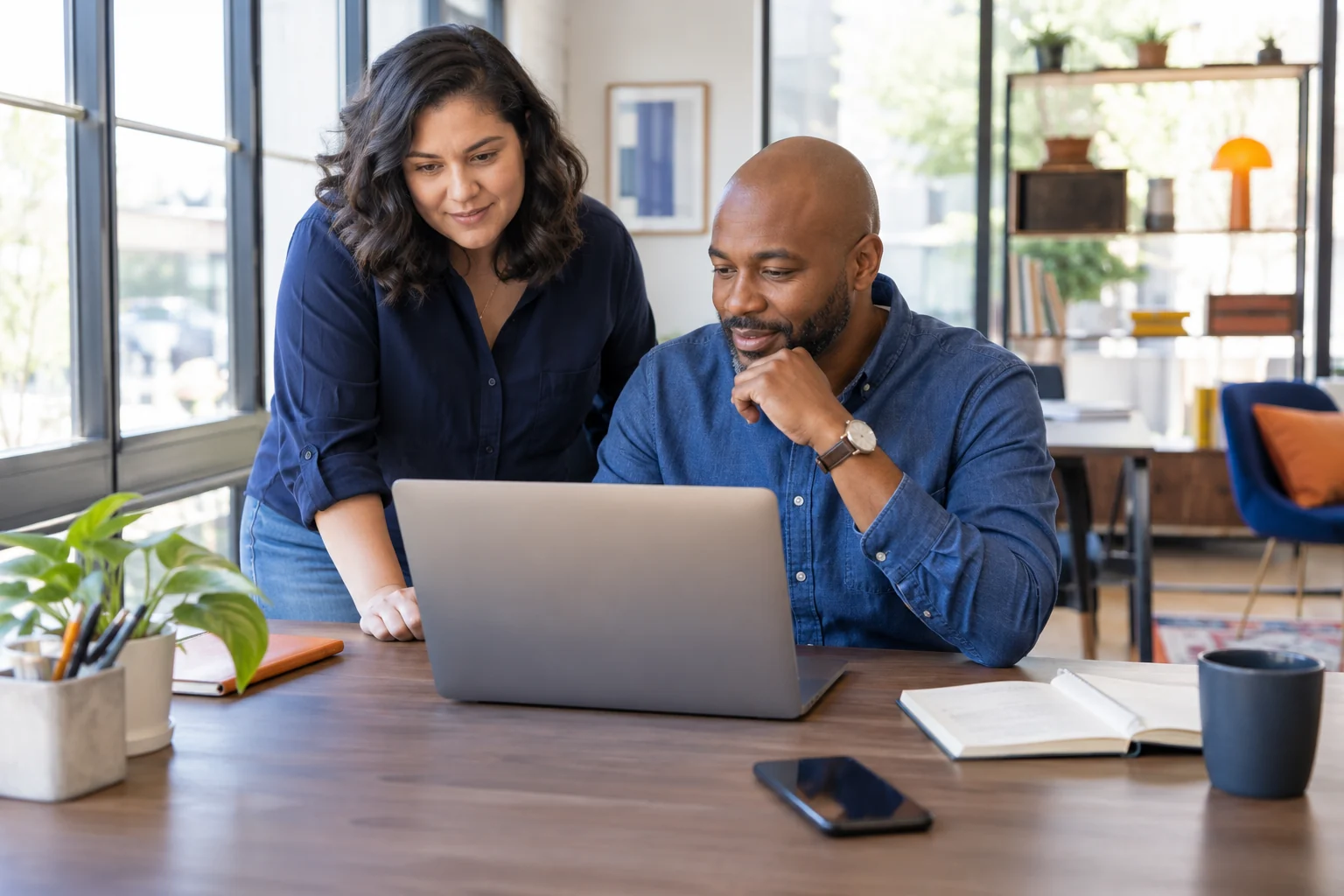 Two colleagues reviewing work together at a laptop